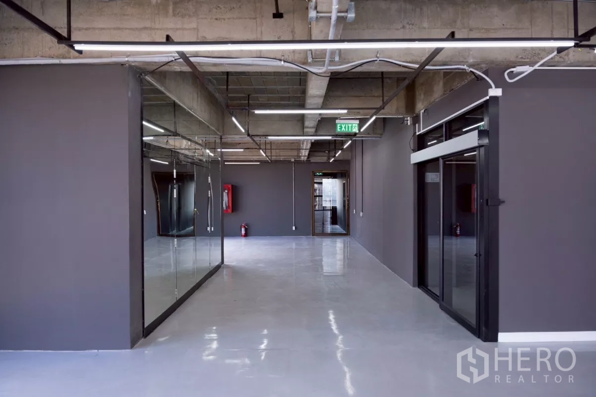 Office Space for rent - Entrance corridor with glass partitions, exit signage and linear lighting.