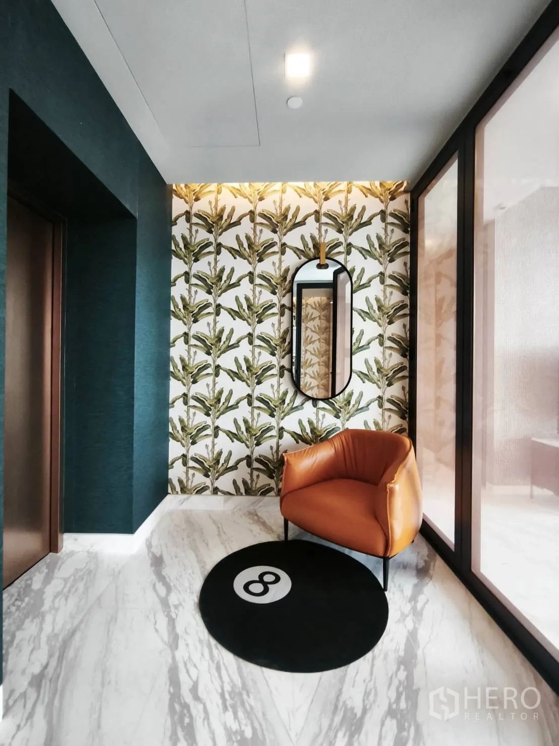 Condominium for rent in Watthana, Bangkok - Stylish foyer with patterned wall, mirror, and orange accent chair.