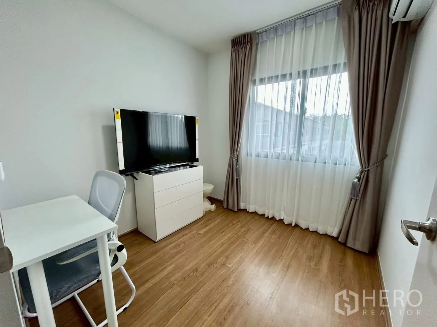 Townhouse for rent in Bang Phli, Samut Prakan - Compact room with desk, TV cabinet and wide window with curtains.