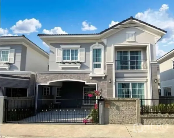 独立式住宅 出售在Bang Khen, Bangkok - 邦肯两层独栋住宅正立面，带车棚、滑动大门与小花园。