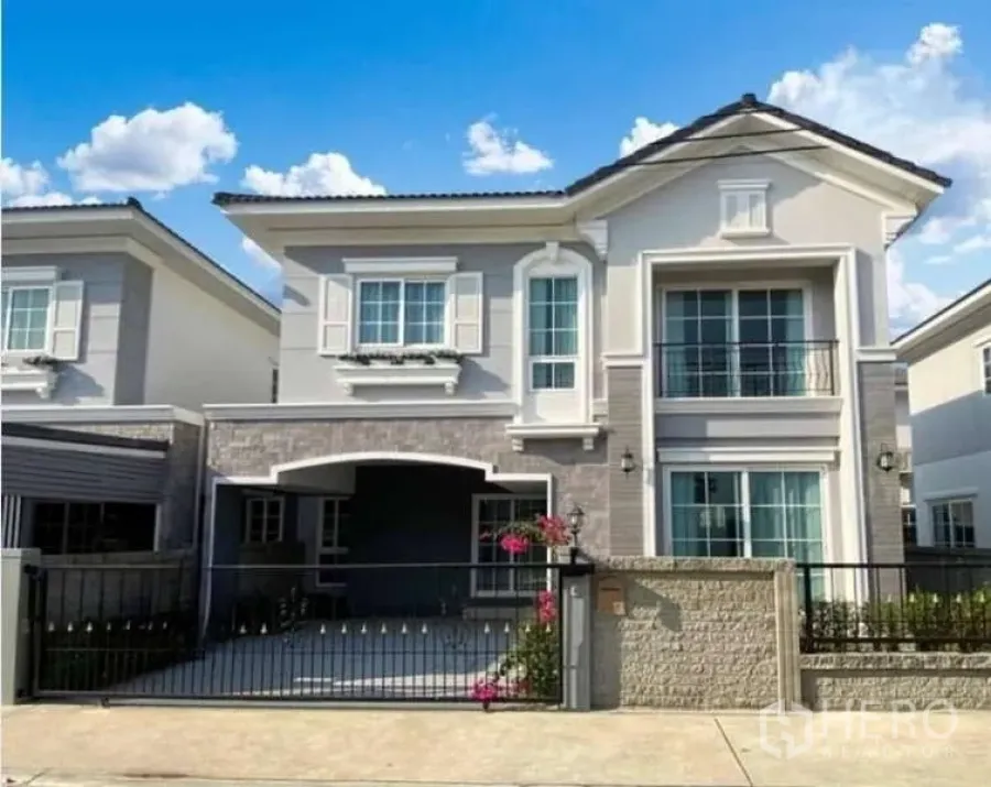 บ้าน ขายในBang Khen, Bangkok - ด้านหน้าบ้านเดี่ยวสองชั้น มีที่จอดรถในร่ม ประตูรั้วเลื่อน และสวนเล็ก