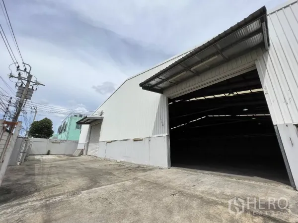 货栈 出租在Sai Mai, Bangkok - 仓库外立面，宽阔混凝土装卸区与大型电动卷帘门，位于曼谷塞迈。