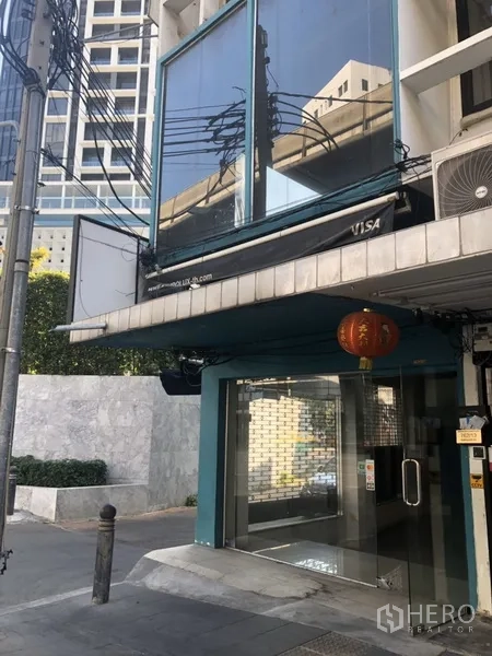 零售空间 出租在Khlong Toei, Bangkok - 临街转角的二层大玻璃窗与街层入口上方的玻璃结构。