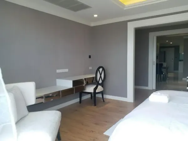 Condominium for rent in Bang Rak, Bangkok - Bright bedroom corner with mirrored built-in desk, accent chair and wood flooring leading to living area.