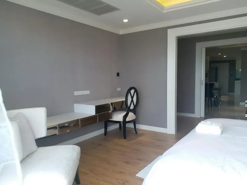 Condominium for rent in Bang Rak, Bangkok - Bright bedroom corner with mirrored built-in desk, accent chair and wood flooring leading to living area.