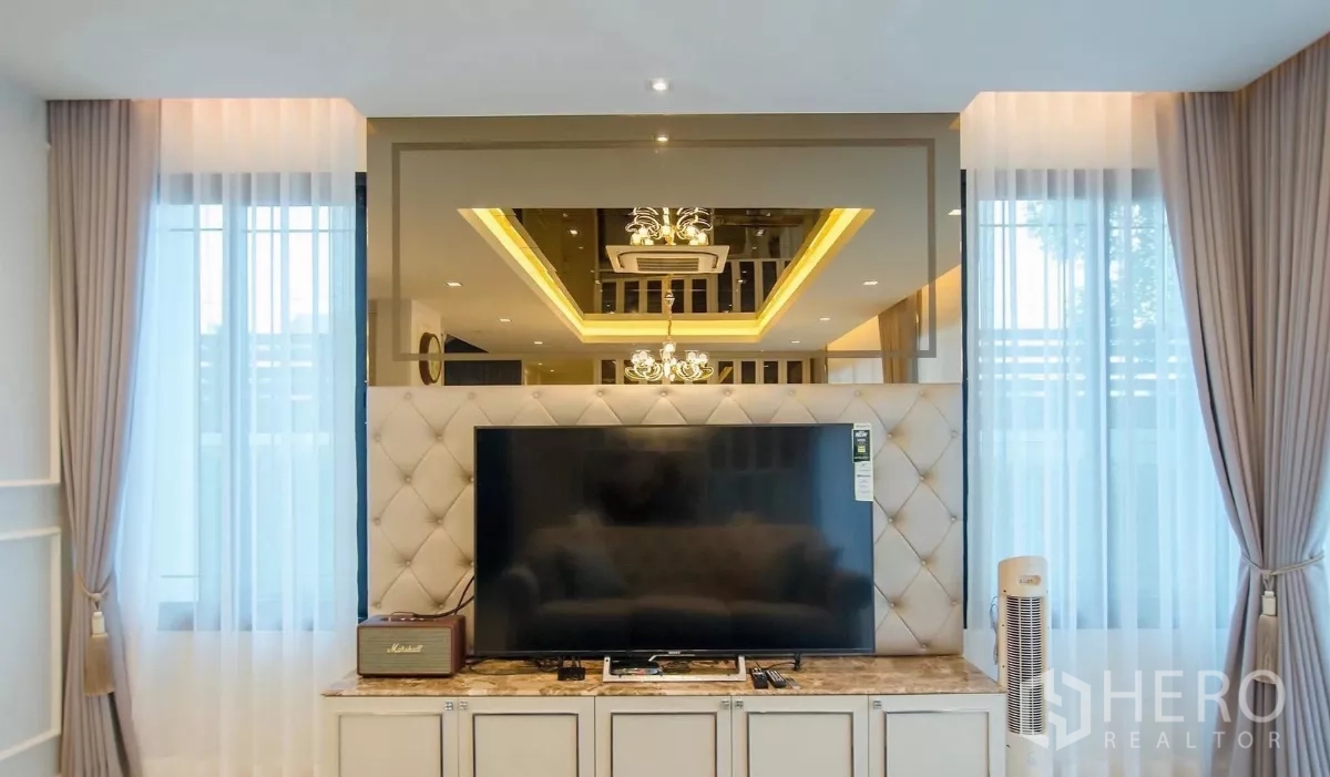 Detached House for rent in Bang Bon, Bangkok - Close-up of TV wall with tufted panel, marble cabinet and large flat-screen TV.