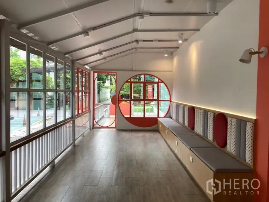 零售空间 出租在Khlong Toei, Bangkok - 明亮的室内零售空间，木纹地板、圆形窗以及整排内置长椅。