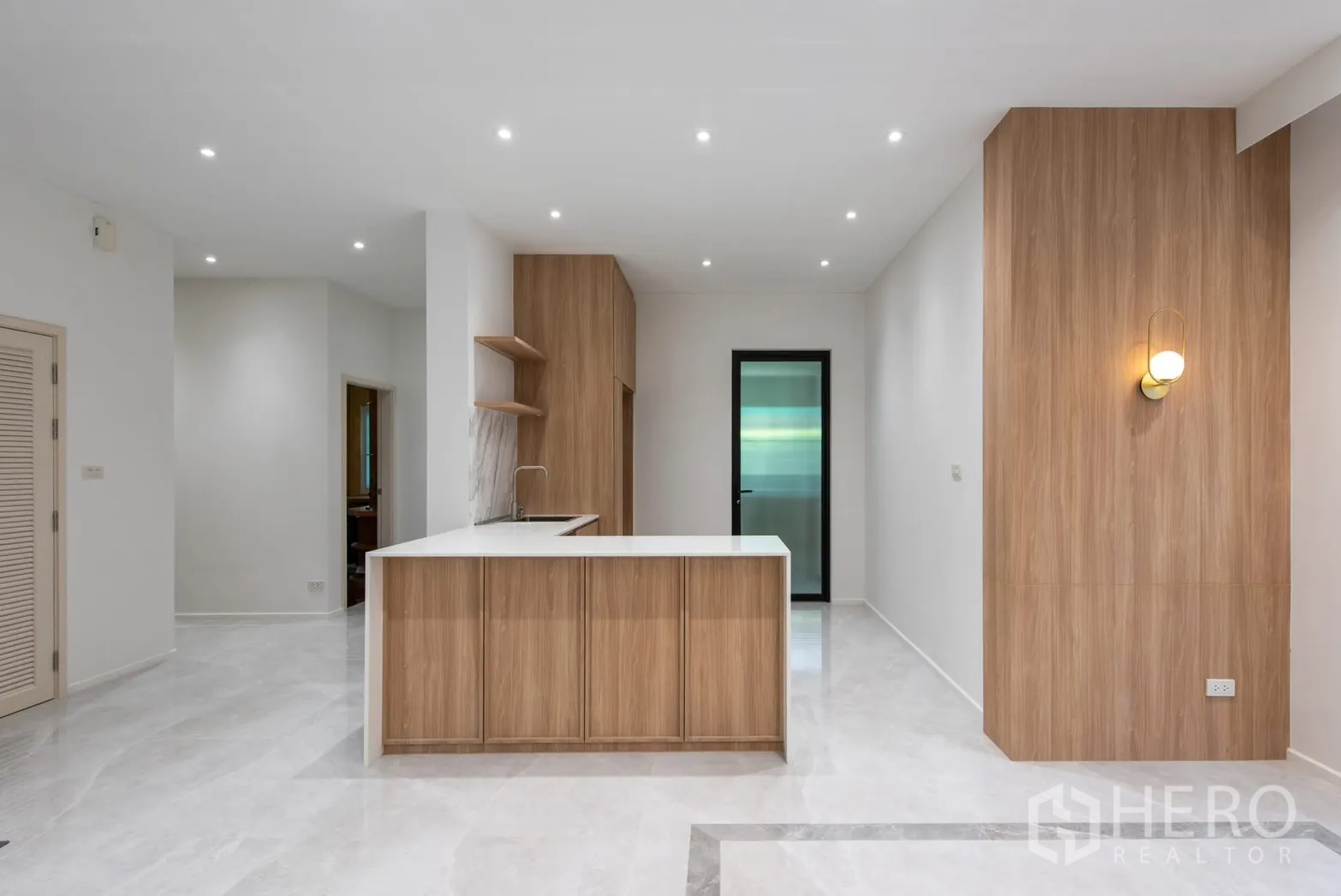 Detached House for sale in Bang Phli, Samut Prakan - Kitchen island with wood panels, marble-look backsplash and recessed lighting.