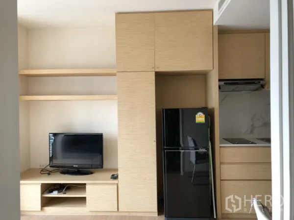 公寓 出租在Khlong Toei, Bangkok - 客厅侧电视柜与开放置物架，旁有高柜与冰箱，动线实用。