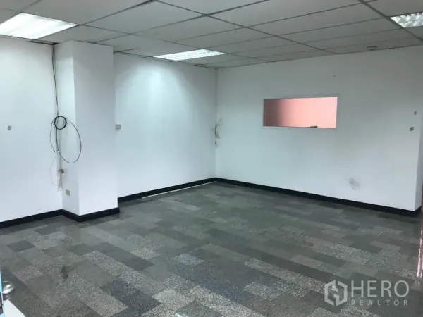 Office Space for rent in Khlong Toei, Bangkok - Open-plan office area with suspended ceiling lights, white walls and visible power and data cabling.