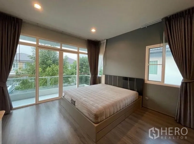 บ้าน ให้เช่าในLat Krabang, Bangkok - ห้องนอนมาสเตอร์พร้อมกระจกเต็มผนังและระเบียงยาวมองเห็นต้นไม้