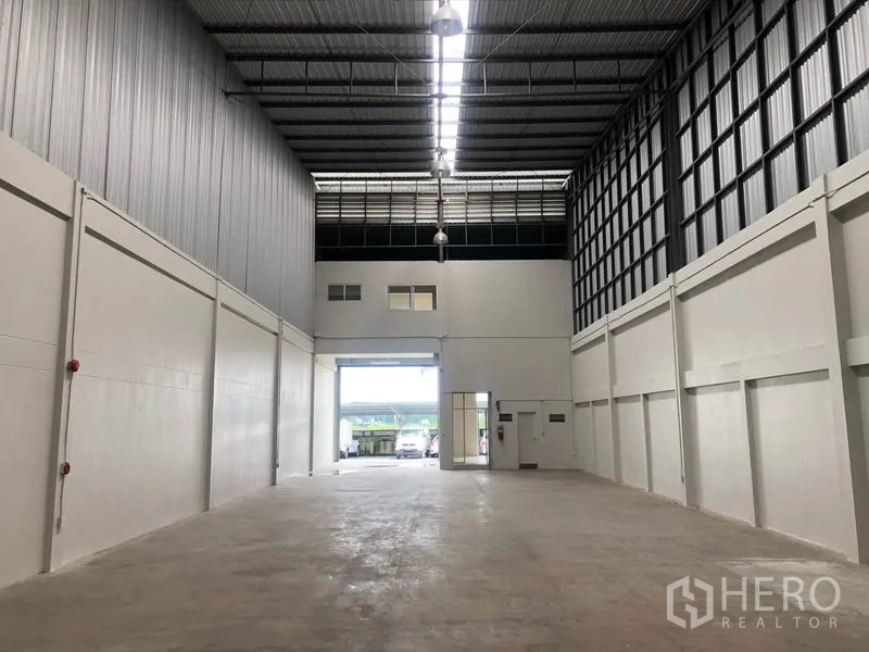 工厂 出租在Pak Kret, Nonthaburi - 仓库内部朝向前部卷闸门，设天窗与吊灯。