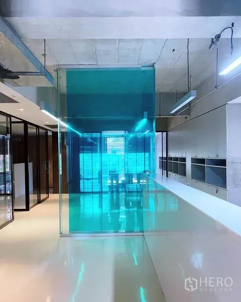 Office Space for rent in Phaya Thai, Bangkok - Modern office interior with polished white flooring, teal glass partition, exposed ceiling lights, and bright natural light.
