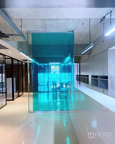 Office Space for rent in Phaya Thai, Bangkok - Modern office interior with polished white flooring, teal glass partition, exposed ceiling lights, and bright natural light.