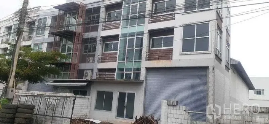 Warehouse for rent in Pathum Thani - Four-story industrial building with attached warehouse and large roller shutter door