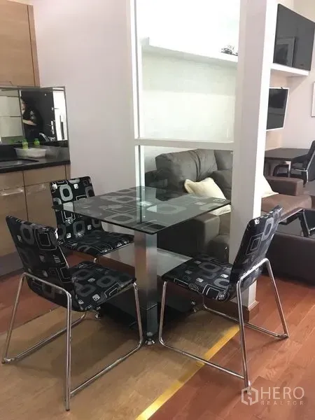 คอนโด ให้เช่าในPathum Wan, Bangkok - โต๊ะรับประทานอาหารกระจกพร้อมเก้าอี้สี่ตัวข้างฉากกั้น มองเห็นโซนนั่งเล่น