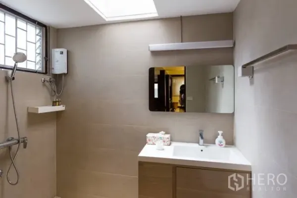 บ้าน ให้เช่าในWatthana, Bangkok - ห้องน้ำสว่าง ผนังสีเบจ เคาน์เตอร์อ่างล้างหน้า ช่องแสงสกายไลท์ และฝักบัวพร้อมเครื่องทำน้ำอุ่น