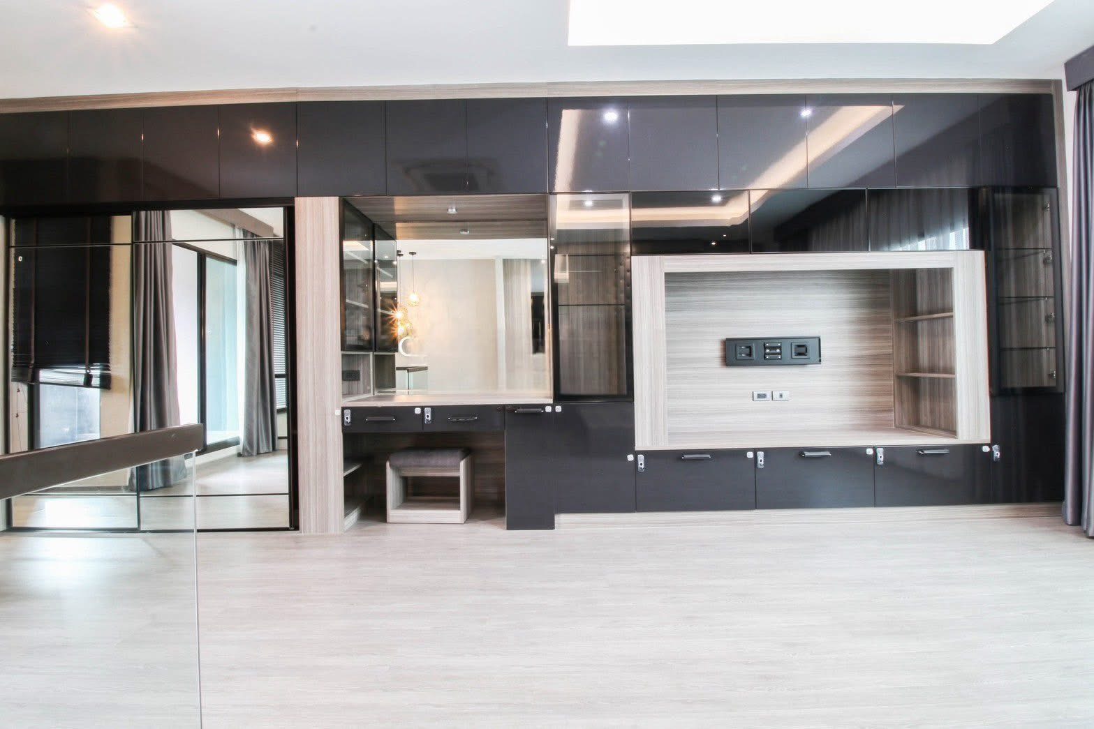 联排别墅 出租或出售在Lat Phrao, Bangkok - 现代房间，整面黑色亮面柜体、镜面与浅木地板。