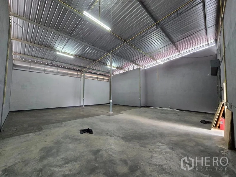 Warehouse for rent in Don Mueang, Bangkok - Spacious warehouse interior with high ceilings, concrete floor, and strip lighting.