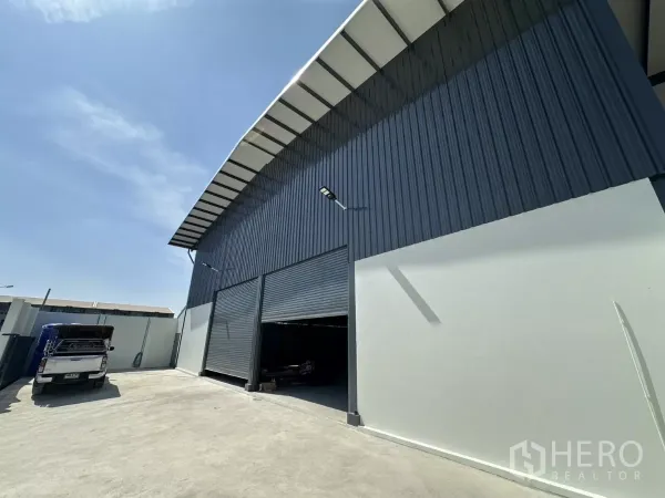 货栈 出租在Prawet, Bangkok - 仓库侧立面，两扇大型卷闸门与宽阔卡车通道。