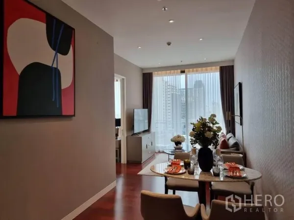 公寓 出租在Watthana, Bangkok - 客餐一体空间，餐桌布置完备，沙发区与落地窗可见曼谷天际线。