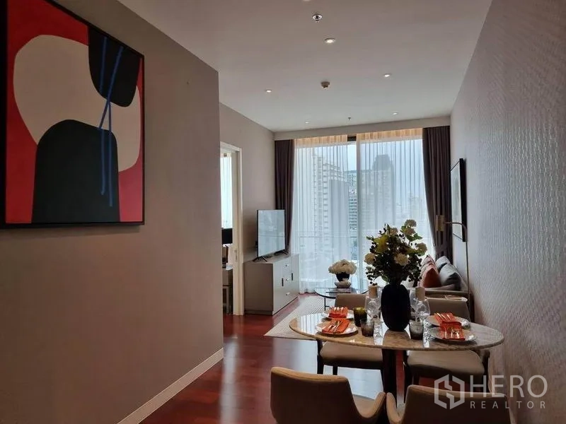 公寓 出租在Watthana, Bangkok - 客餐一体空间，餐桌布置完备，沙发区与落地窗可见曼谷天际线。