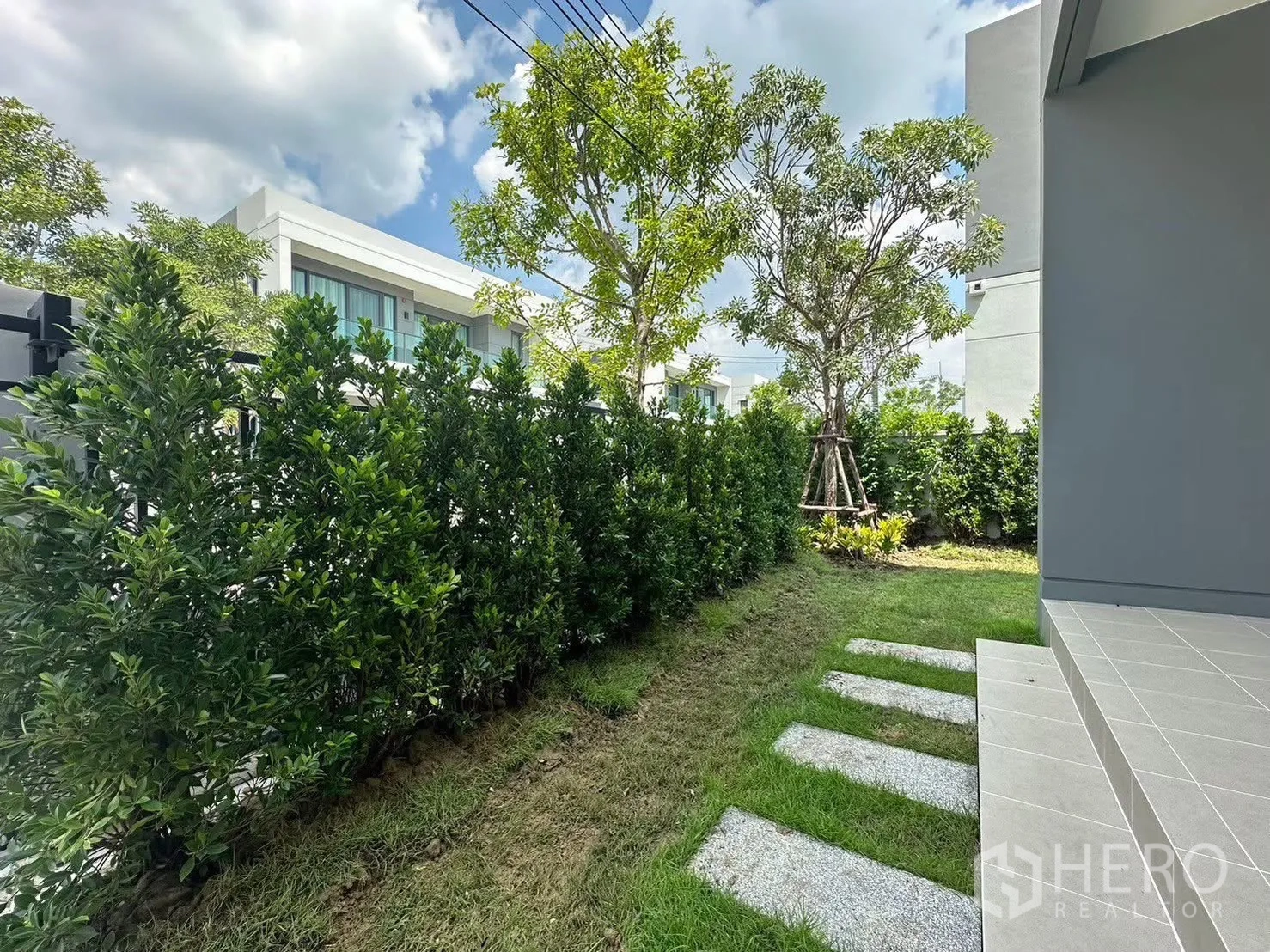 Detached House for rent in Bang Phli, Samut Prakan - Front garden with stepping stones, tall hedge fence and a shaded porch.