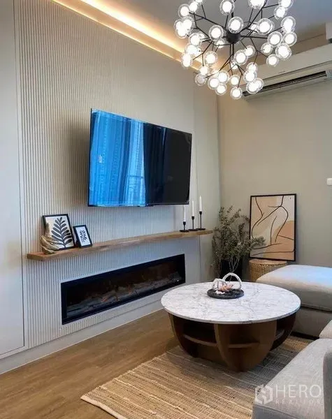 คอนโด ให้เช่าในRatchathewi, Bangkok - ห้องรับแขกสไตล์โมเดิร์น มีโคมไฟระย้า ทีวีติดผนัง เตาผิงไฟฟ้า และโต๊ะกลางหินอ่อนบนพื้นไม้