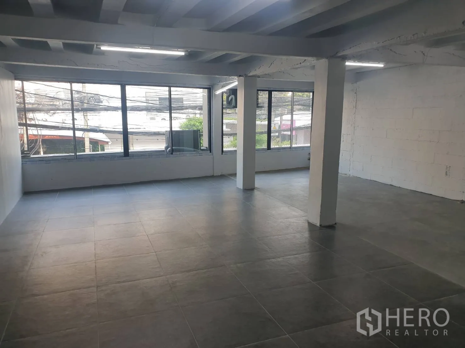 零售空间 出租在Khlong Toei, Bangkok - 宽敞零售楼层，整面大窗临街视野，外露梁顶与瓷砖地面。