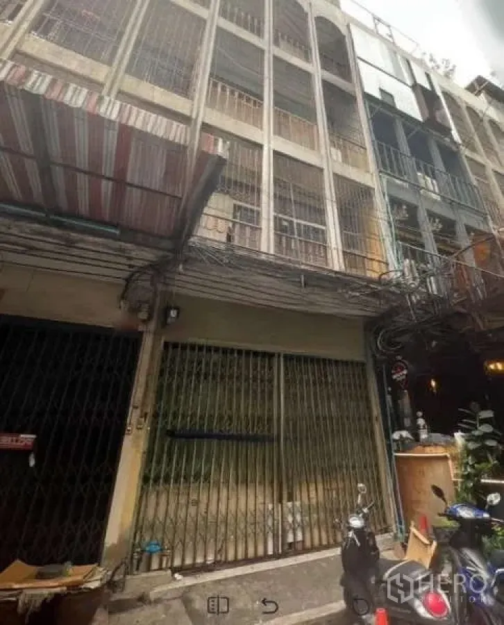 อาคารพาณิชย์ ให้เช่าในKhlong Toei, Bangkok - ด้านหน้าตึกแถว 4 ชั้น ประตูเหล็กยืด ระเบียงมีลูกกรงในซอยแคบ