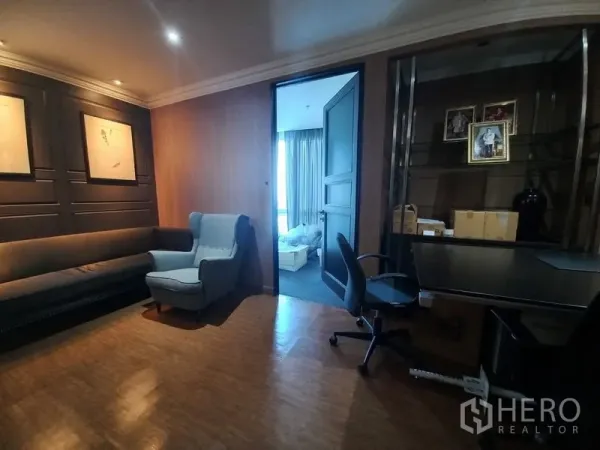 Office Space for rent - Cozy office lounge with long sofa, armchair, built-in shelving and doorway to a bright meeting room.