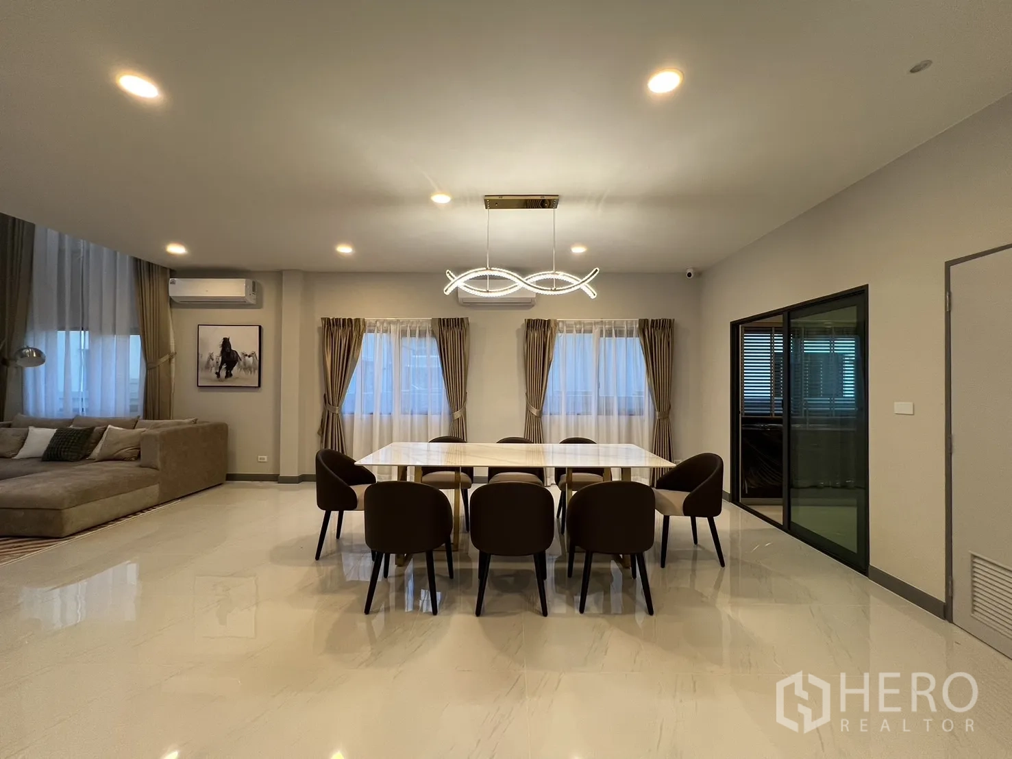 Detached House for rent or sale in Bang Phli, Samut Prakan - Spacious dining area with eight-seat marble table and contemporary chandelier.