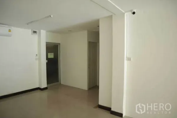 零售空间 出租在Watthana, Bangkok - 店内角落带卫生间门、壁挂空调与小型储物区。