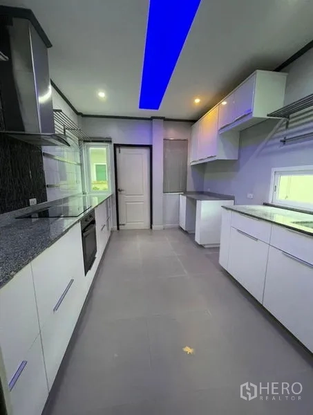 独立式住宅 出售在Bang Phli, Samut Prakan - 现代走廊式厨房，白色橱柜、石材台面与LED灯带。