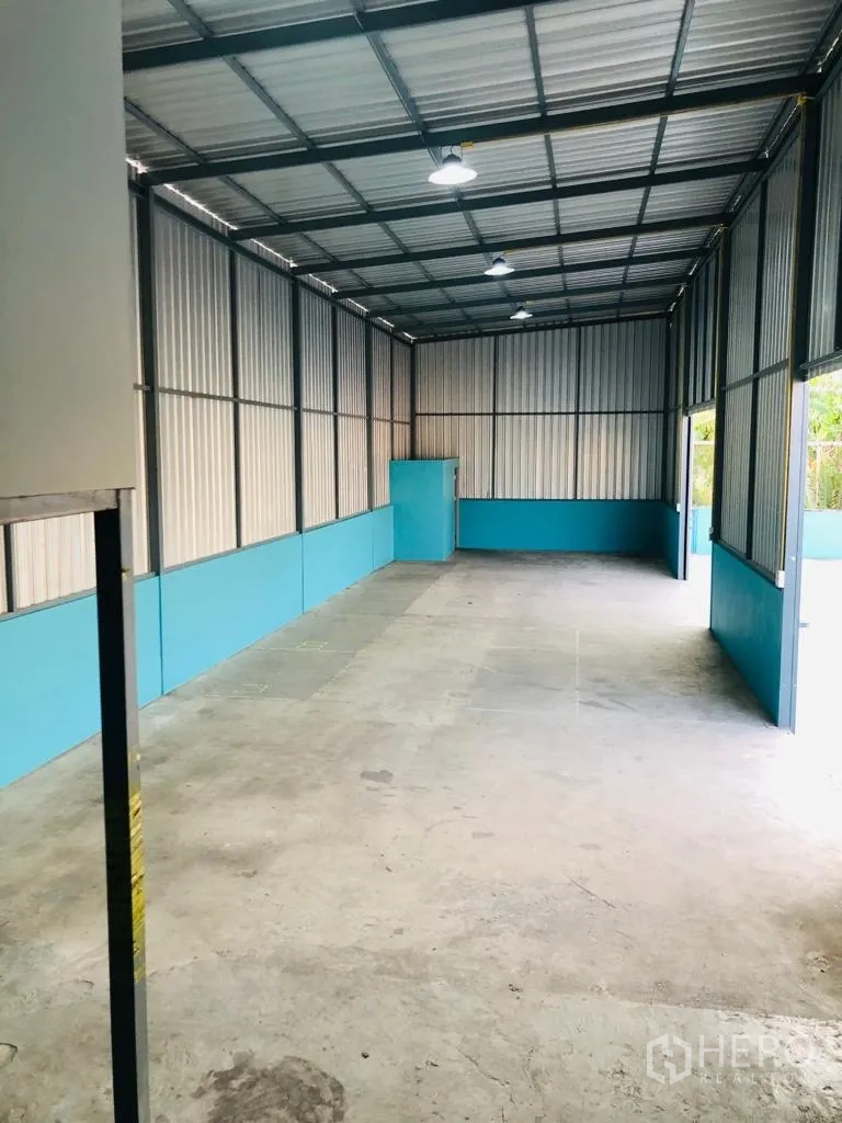 คลังสินค้า ให้เช่าในSaphan Sung, Bangkok - มุมมองภายในโกดังแบบยาว เห็นไฟแขวน เพดานสูง ผนังทาสีฟ้าและพื้นคอนกรีตเรียบ