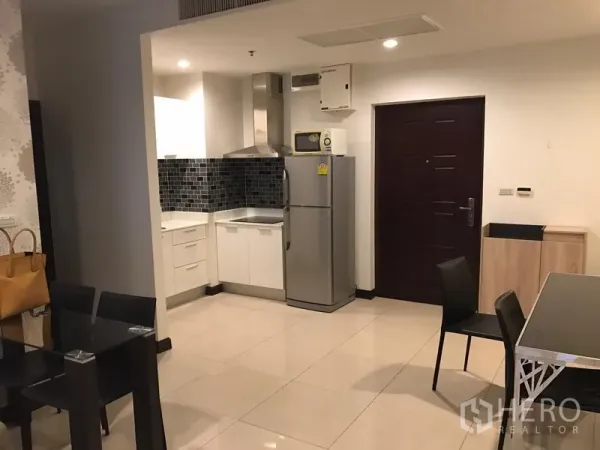 公寓 出租在Watthana, Bangkok - 开放式厨房，白色橱柜、黑色拼贴墙面、不锈钢冰箱与抽油烟机，旁连就餐区