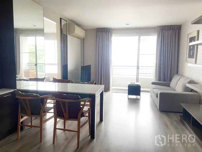 Condominium for rent in Watthana, Bangkok - Open-plan living and dining room with sofa, dining set and large balcony doors letting in natural light.