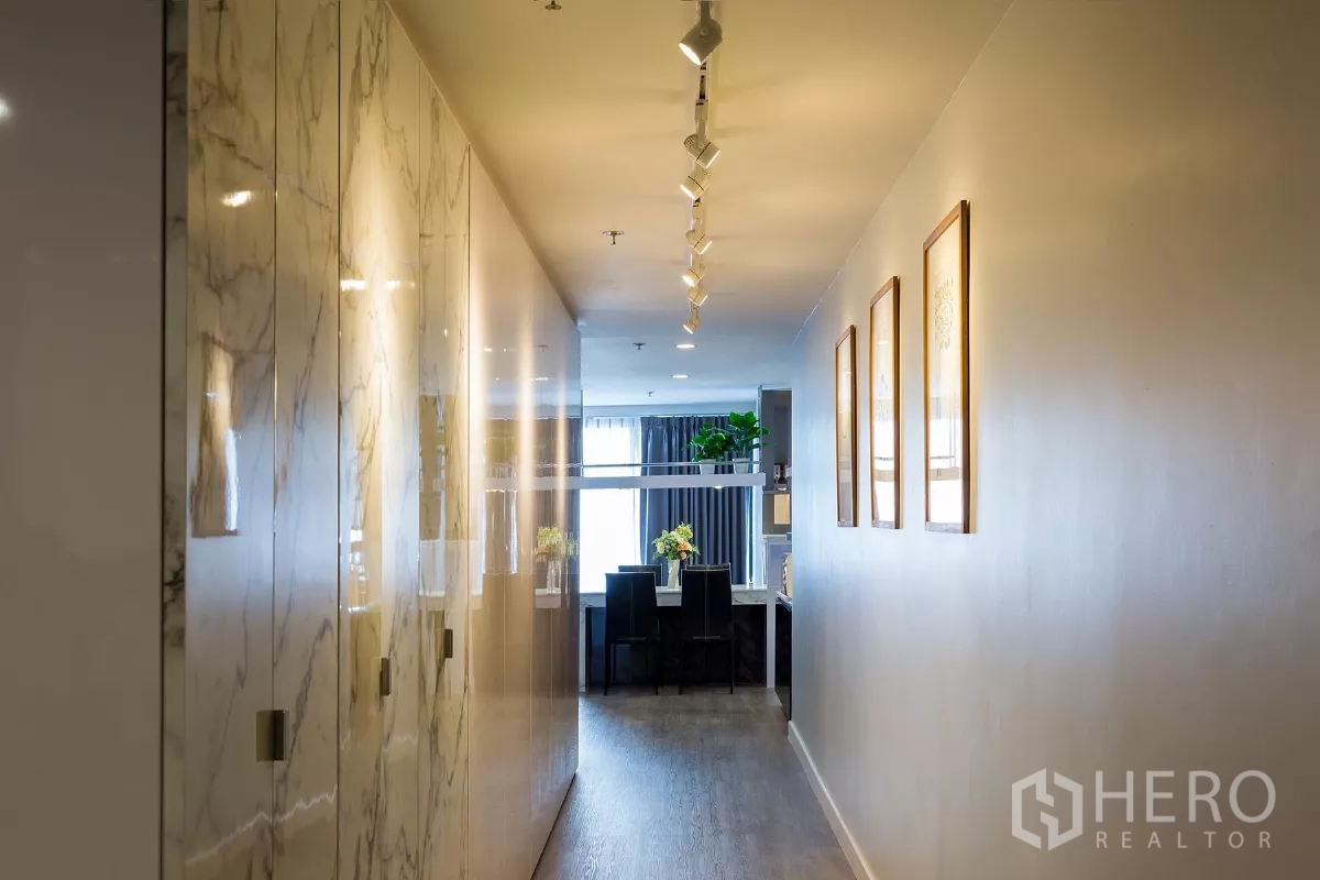 Condominium for rent or sale in Watthana, Bangkok - Hallway with marble built-in cabinets, track lighting and sightline to the dining area.