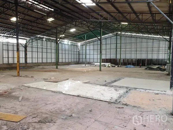 Warehouse for rent in Mueang Nonthaburi, Nonthaburi - Spacious warehouse interior with steel truss roof, high ceilings, metal sheet walls and open concrete flooring.
