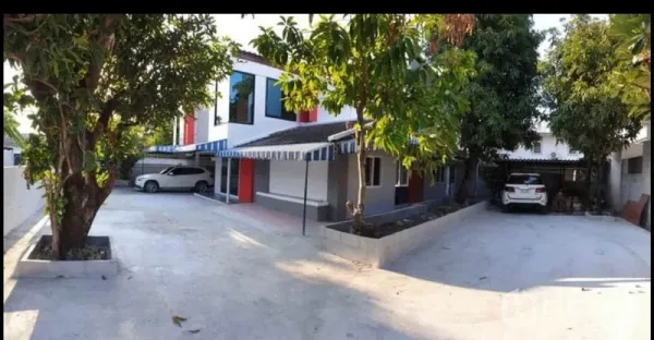 独立式住宅 出租在Lat Phrao, Bangkok - 曼谷拉抛两层独栋别墅外观，宽阔水泥车道、成荫大树与双车位车棚。