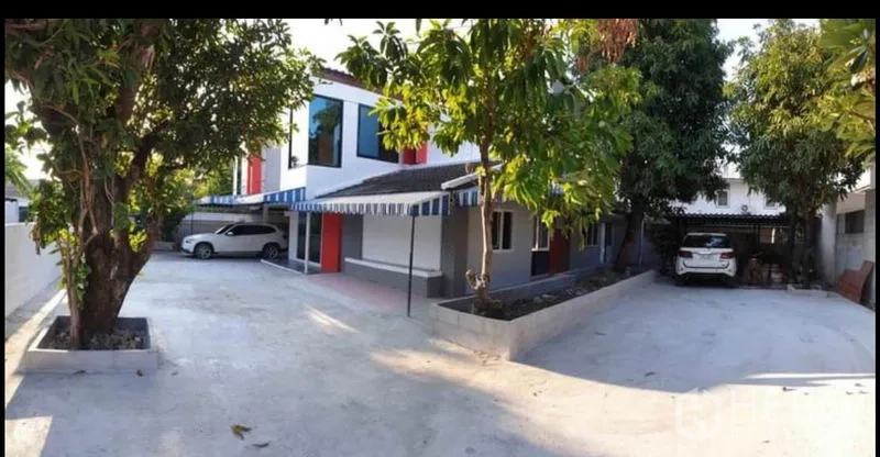 บ้าน ให้เช่าในLat Phrao, Bangkok - ด้านหน้าบ้านเดี่ยวสองชั้นย่านลาดพร้าว ลานจอดรถกว้าง มีต้นไม้ใหญ่และโรงจอดรถสองฝั่ง
