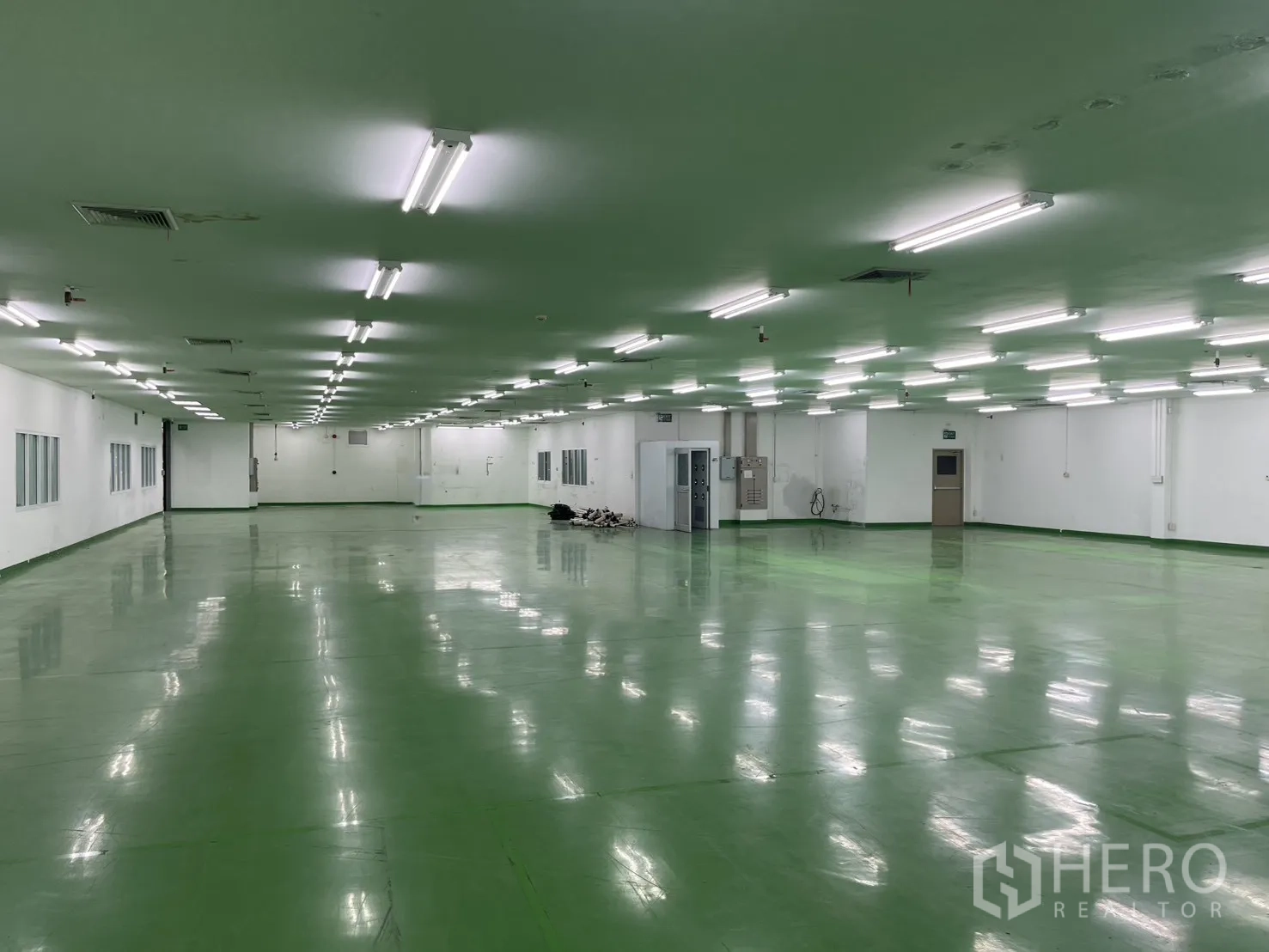 Factory for rent in Mueang Samut Prakan, Samut Prakan - Spacious indoor factory space with white walls, office windows, electrical panels and multiple doors.