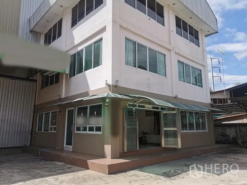 Factory for rent in Mueang Chachoengsao, Chachoengsao - Three‑storey office block with large windows and awnings beside the factory entrance.