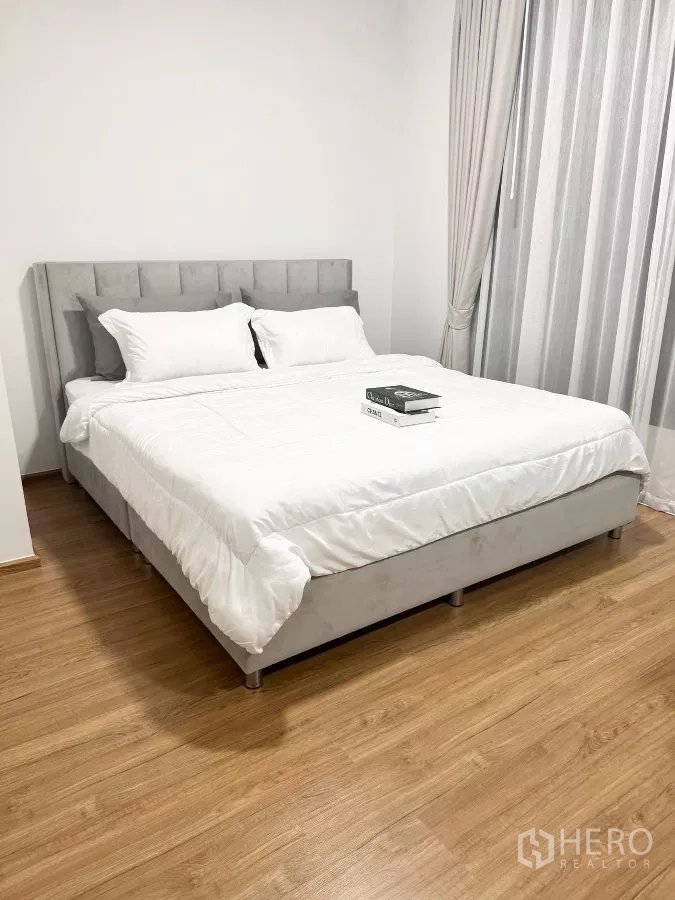 Townhouse for rent in Bang Phli, Samut Prakan - Master bedroom with king-size bed, wood flooring and full-length curtains.