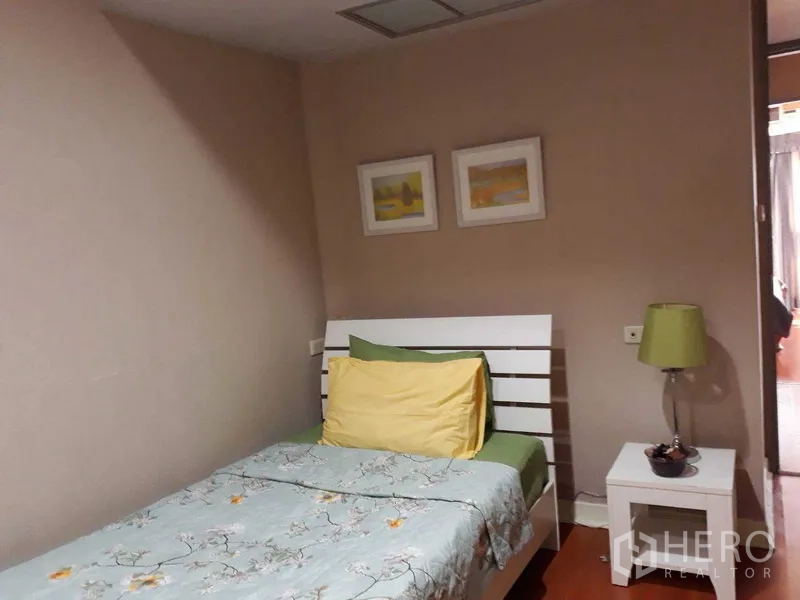 公寓 出租或出售在Khlong Toei, Bangkok - 单人卧室，白色床架与床头灯，中性色墙面和装饰画。