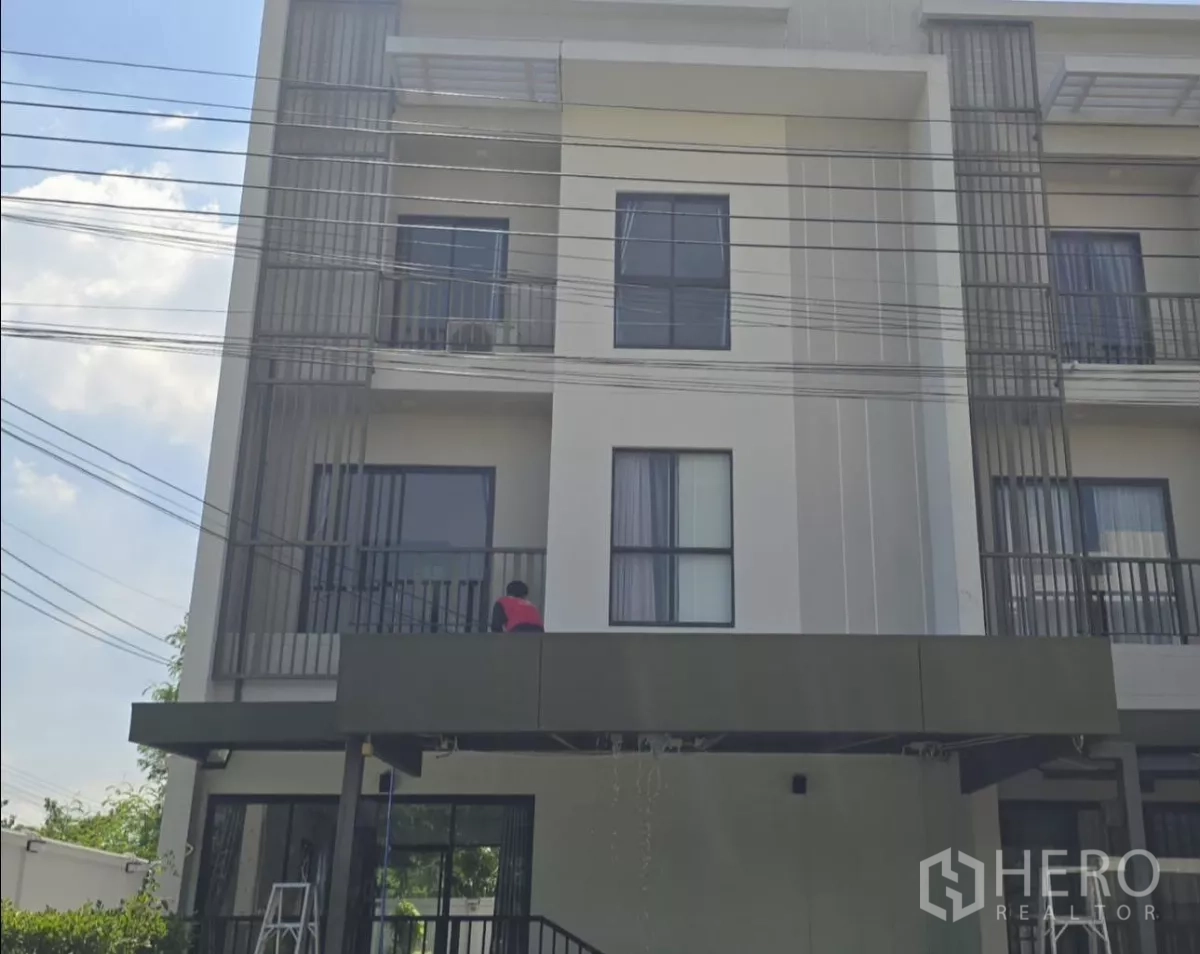 Townhouse for rent or sale in Saphan Sung, Bangkok - Modern three-storey townhouse facade with balconies and covered carport.