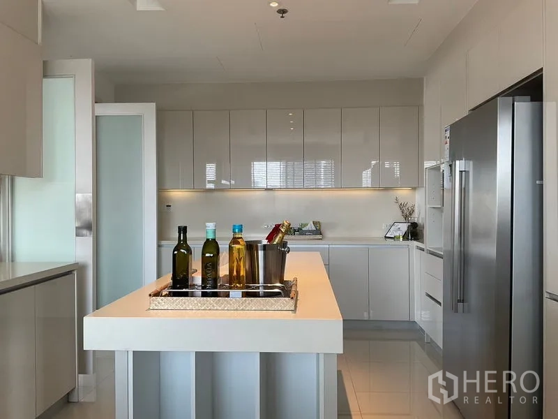 房间 出租在Sathon, Bangkok - 厨房岛台与整墙柜，柔和灯光。