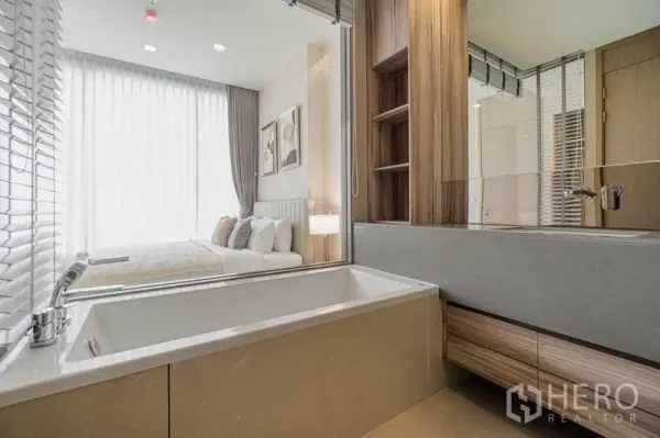 Condominium for rent in Watthana, Bangkok - Contemporary bathroom with soaking tub and glass partition looking into the bedroom.