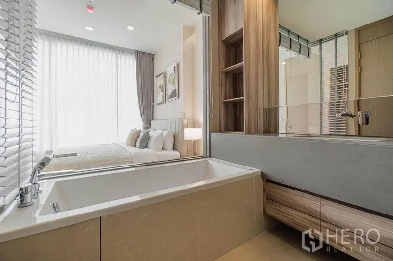 Condominium for rent in Watthana, Bangkok - Contemporary bathroom with soaking tub and glass partition looking into the bedroom.