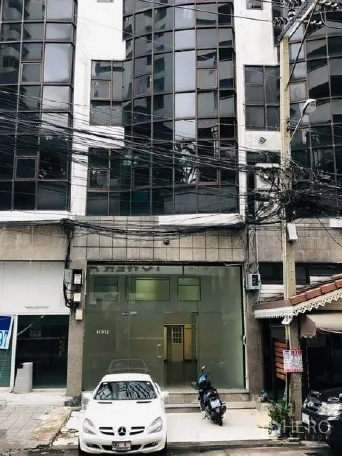 Office Space for rent in Khlong Toei, Bangkok - Commercial building exterior with glass facade and on-street parking in Khlong Toei.